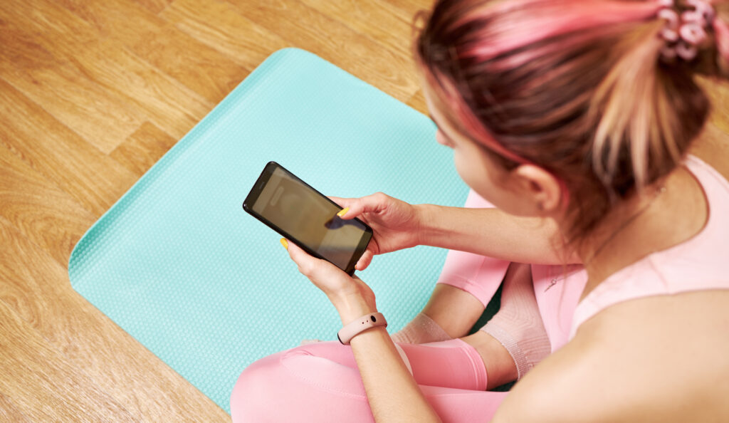 Woman with phone on Yoga matt