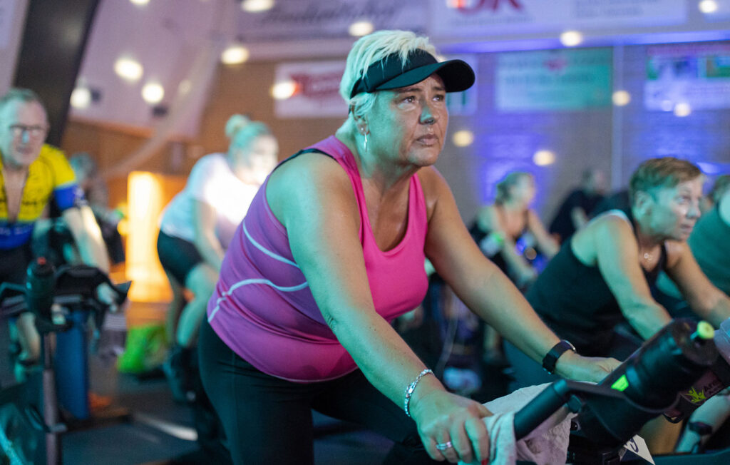 Woman with sports cap in indoor cycling class