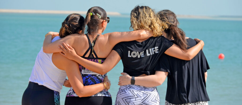 four girls arm in arm in front of the sea